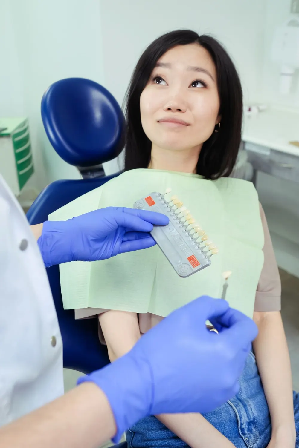 Dokter gigi mencocokkan warna gigi pasien dengan shade guide